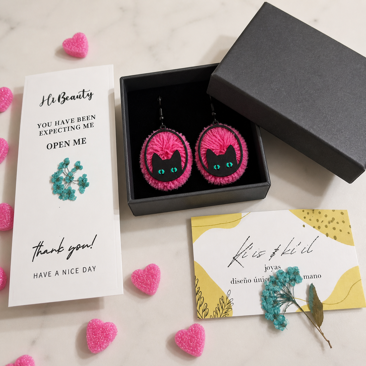 Pendientes con pompones rosa intenso y detalle de gato negro